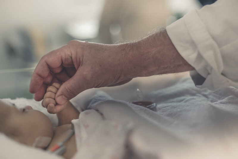 mano di medico tiene la mano di un neonato